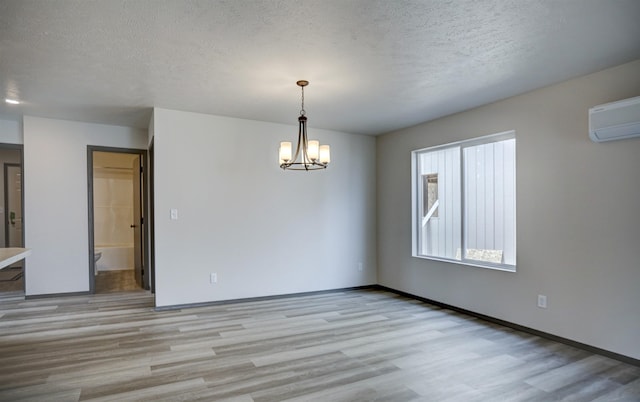 18509 E Michielli Ln, Spokane Valley, WA 99016 - spare room featuring light wood-style floors, a chandelier, a textured ceiling, a wall mounted AC, and baseboards