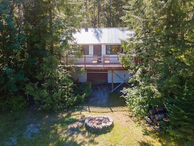 2948 Deep Lake Boundary Rd, Colville, WA 99114 - back of property with a fire pit, driveway, metal roof, a deck, and an attached garage