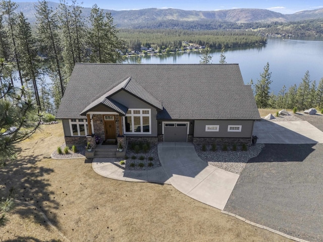 6595D Lois Way, Nine Mile Falls, WA 99026 - view of front of home with stone siding, a water and mountain view, concrete driveway, a shingled roof, and an attached garage