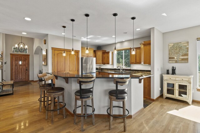 6595D Lois Way, Nine Mile Falls, WA 99026 - kitchen with freestanding refrigerator, dark countertops, light wood-type flooring, a breakfast bar, and arched walkways