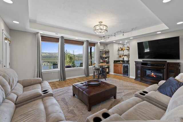 6595D Lois Way, Nine Mile Falls, WA 99026 - living area featuring beverage cooler, a raised ceiling, bar with sink, recessed lighting, and light wood finished floors