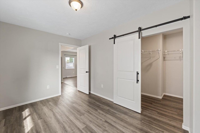 10 S Greenacres Ave, Spokane Valley, WA 99016 - unfurnished bedroom with wood finished floors, a barn door, baseboards, a closet, and a textured ceiling