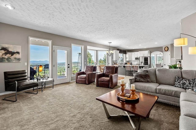 10409 E Grouse Mountain Ln, Spokane, WA 99206 - living area with healthy amount of natural light, a textured ceiling, a chandelier, light carpet, and arched walkways