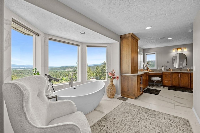 10409 E Grouse Mountain Ln, Spokane, WA 99206 - full bathroom featuring a textured ceiling, a freestanding tub, vanity, marble finish flooring, and recessed lighting