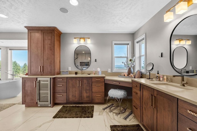 10409 E Grouse Mountain Ln, Spokane, WA 99206 - full bathroom with wine cooler, a textured ceiling, two vanities, a freestanding bath, and marble finish floors