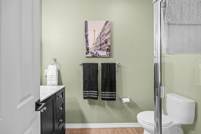 10409 E Grouse Mountain Ln, Spokane, WA 99206 - full bathroom featuring toilet, wood finished floors, vanity, baseboards, and an enclosed shower