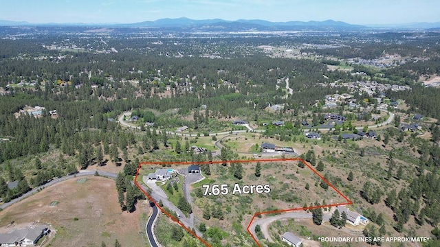 10409 E Grouse Mountain Ln, Spokane, WA 99206 - aerial view of property and surrounding area with a mountainous background, property parcel outlined, and a heavily wooded area