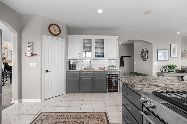 10409 E Grouse Mountain Ln, Spokane, WA 99206 - kitchen with wine cooler, gray cabinetry, white cabinetry, arched walkways, and a textured ceiling