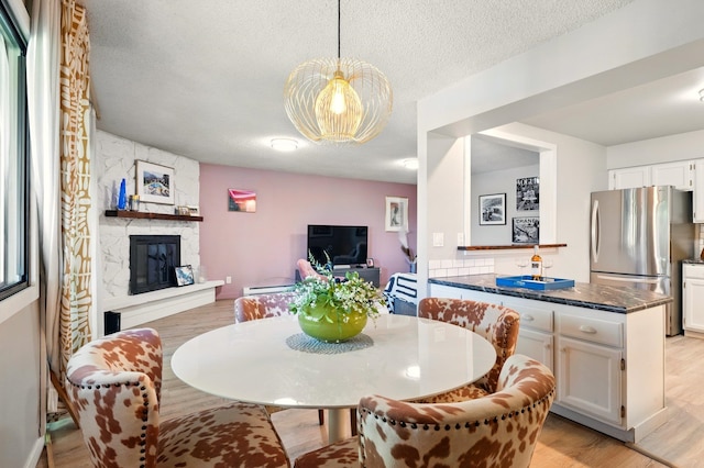1002 W 7th Ave Unit 302, Spokane, WA 99204 - dining room with a fireplace, a textured ceiling, light wood finished floors, baseboard heating, and a chandelier