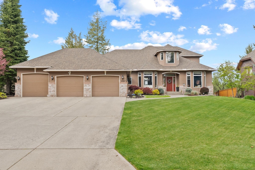 504 W Wilson Ct, Spokane, WA 99208 - view of front of home featuring an attached garage, concrete driveway, stone siding, and a shingled roof