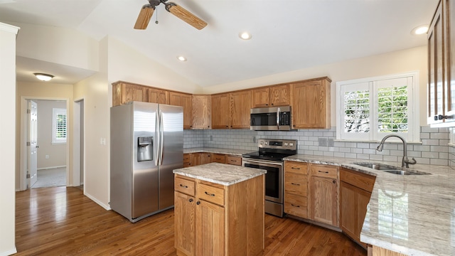 3404 W Excell Ave, Spokane, WA 99208 - kitchen with stainless steel appliances, a sink, a kitchen island, light stone counters, and vaulted ceiling
