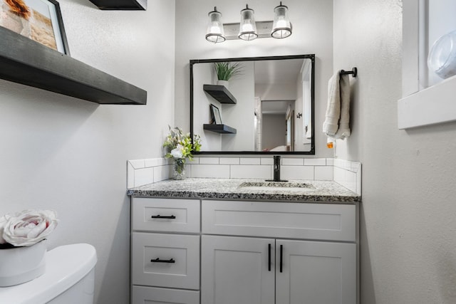 12327 E Sioux Cir, Spokane Valley, WA 99206 - bathroom featuring vanity, toilet, and decorative backsplash