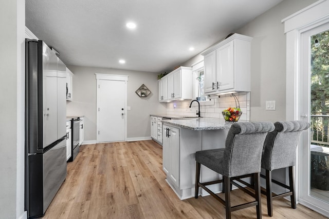 12327 E Sioux Cir, Spokane Valley, WA 99206 - kitchen featuring stainless steel appliances, a peninsula, white cabinets, tasteful backsplash, and light stone counters