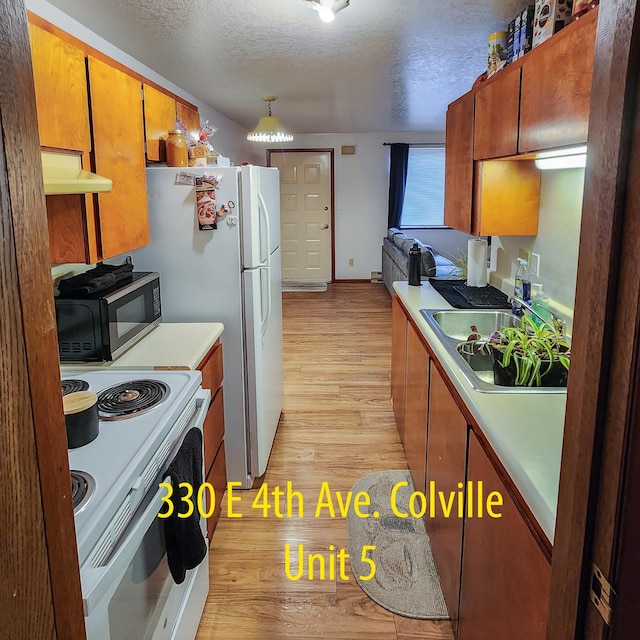 330 E 4th Ave, Colville, WA 99114 - kitchen with white electric range oven, light wood-style floors, under cabinet range hood, a textured ceiling, and brown cabinets