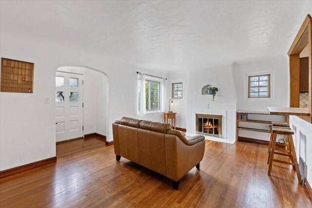 10503 E Valleyway Ave, Spokane Valley, WA 99206 - living room featuring arched walkways, wood finished floors, a glass covered fireplace, and baseboards