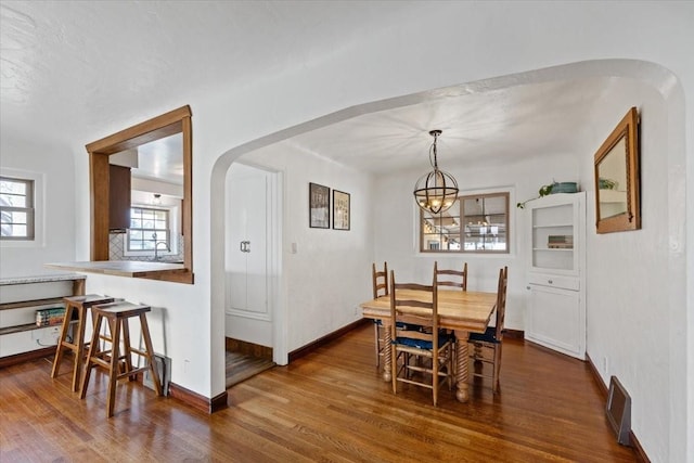 10503 E Valleyway Ave, Spokane Valley, WA 99206 - dining room with arched walkways, dark wood-type flooring, a chandelier, and baseboards