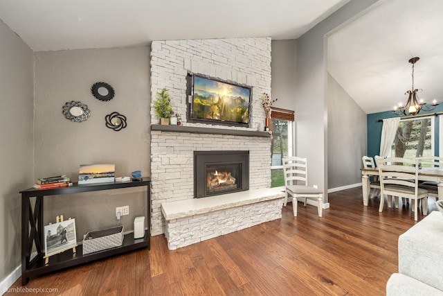 4116 W Indian Trail Rd, Spokane, WA 99208 - living area featuring vaulted ceiling, a chandelier, a stone fireplace, baseboards, and wood finished floors