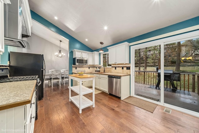 4116 W Indian Trail Rd, Spokane, WA 99208 - kitchen with appliances with stainless steel finishes, a sink, decorative backsplash, decorative light fixtures, and lofted ceiling