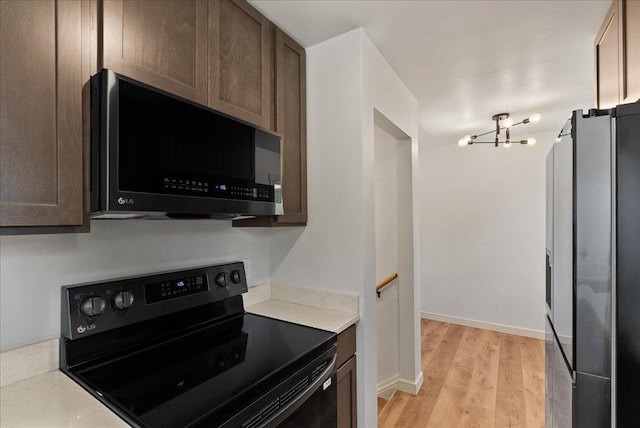 1403 N Farr Rd, Spokane, WA 99206 - kitchen featuring black appliances, light countertops, light wood-style flooring, a chandelier, and baseboards