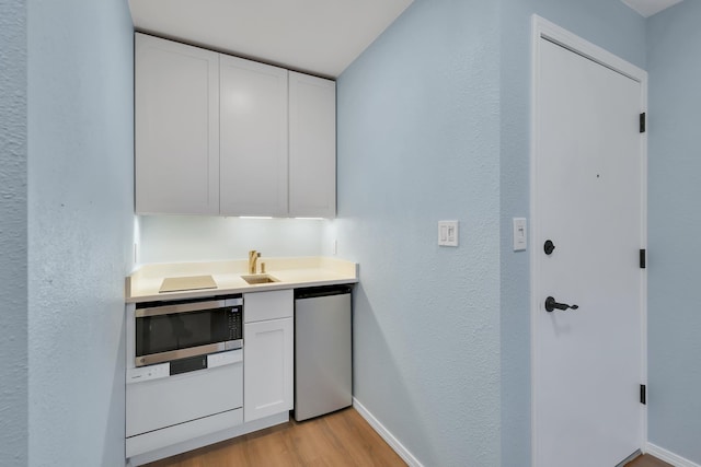 28600 N Mt Spokane Park Dr Unit 603, Mead, WA 99021 - kitchen featuring stainless steel microwave, white cabinetry, light wood-type flooring, baseboards, and a textured wall