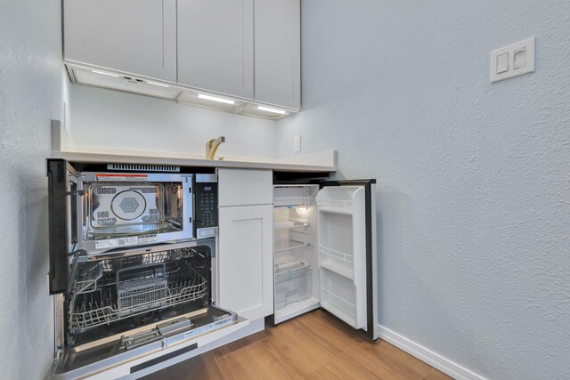 28600 N Mt Spokane Park Dr Unit 603, Mead, WA 99021 - kitchen view of wood finished floors, a textured wall, baseboards, and black microwave