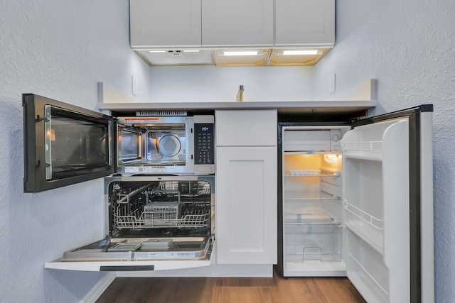 28600 N Mt Spokane Park Dr Unit 603, Mead, WA 99021 - kitchen view of wood finished floors, refrigerator, a textured wall, and white cabinets