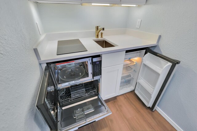 28600 N Mt Spokane Park Dr Unit 603, Mead, WA 99021 - kitchen with a sink, a textured wall, wood finished floors, white cabinets, and light countertops