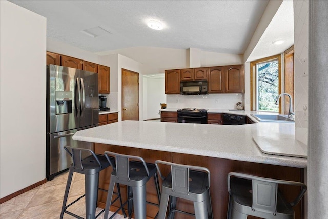 4510 E Bixel Ct, Mead, WA 99021 - kitchen with black appliances, a sink, a peninsula, light countertops, and a kitchen bar