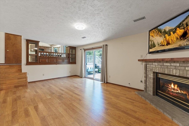 4510 E Bixel Ct, Mead, WA 99021 - unfurnished living room featuring a fireplace, light wood finished floors, a textured ceiling, baseboards, and stairway