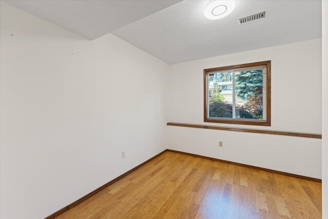 4510 E Bixel Ct, Mead, WA 99021 - unfurnished room with light wood-style floors, baseboards, vaulted ceiling, and a textured ceiling