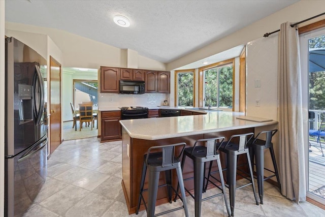 4510 E Bixel Ct, Mead, WA 99021 - kitchen with black appliances, a peninsula, light countertops, a breakfast bar area, and a textured ceiling