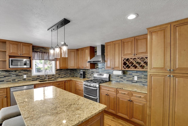 7312 E Euclid Ave, Spokane Valley, WA 99212 - kitchen with appliances with stainless steel finishes, wall chimney range hood, a sink, a kitchen island, and light stone countertops