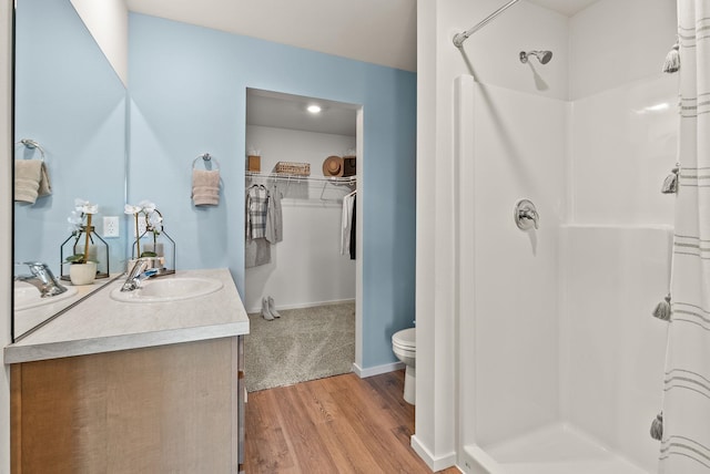 5111 E Frederick Ave, Spokane, WA 99217 - bathroom featuring a stall shower, vanity, wood finished floors, a walk in closet, and toilet