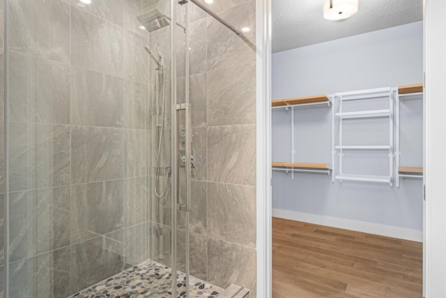 20168 E 11th Ln, Greenacres, WA 99016 - bathroom featuring a stall shower, wood finished floors, a spacious closet, and baseboards