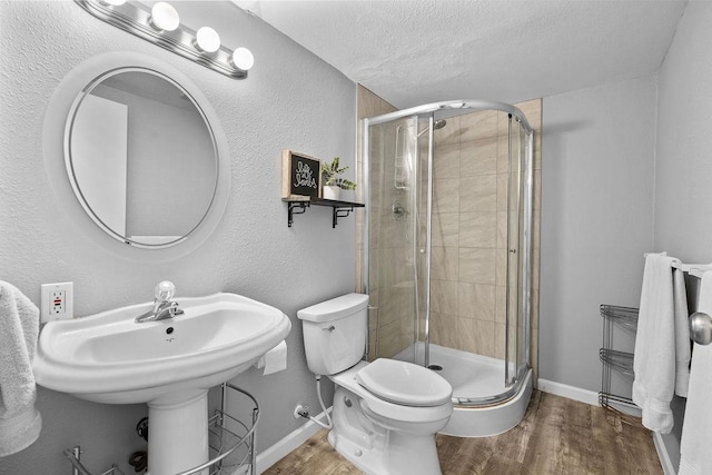 4238 E 24th Ave, Spokane, WA 99223 - bathroom featuring wood finished floors, a stall shower, a textured ceiling, toilet, and baseboards