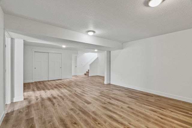 1217 E Granary Ct, Spokane, WA 99208 - finished below grade area with light wood-type flooring, a textured ceiling, baseboards, and stairway