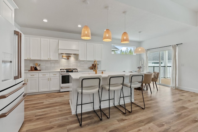 1217 E Granary Ct, Spokane, WA 99208 - kitchen featuring gas range oven, white fridge with ice dispenser, light countertops, light wood-style flooring, and a kitchen breakfast bar