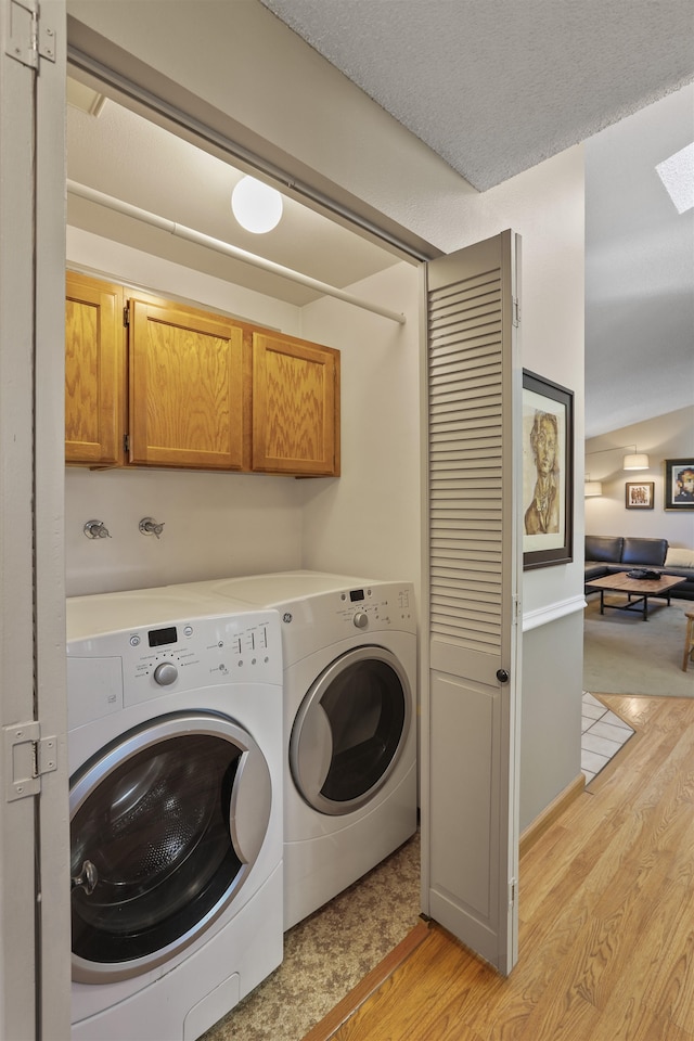 3014 S Perry St Unit 3014, Spokane, WA 99203 - laundry room featuring cabinet space, light wood-type flooring, washing machine and dryer, and a skylight