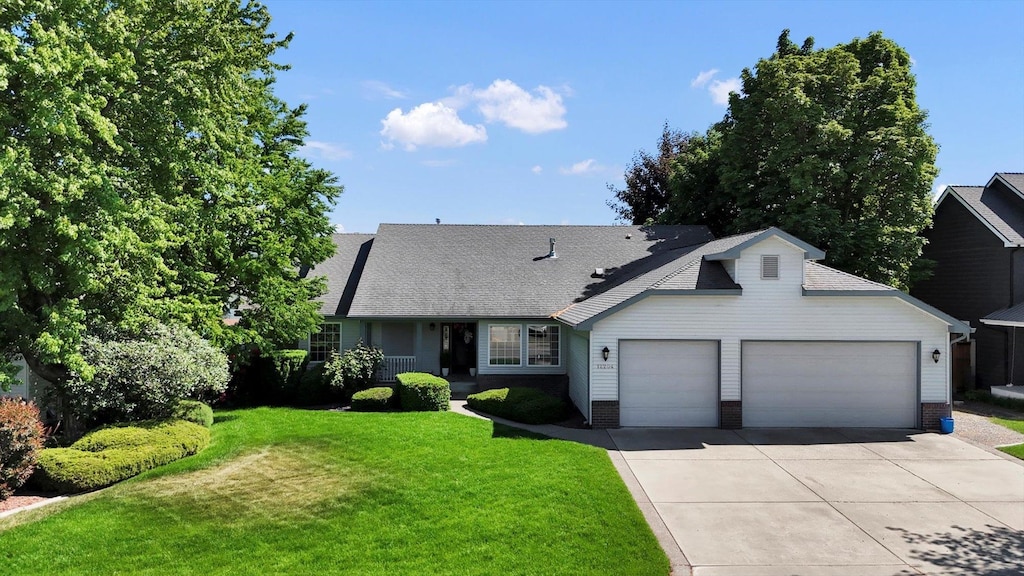12204 E 38th Ave, Spokane Valley, WA 99206 - view of front facade with an attached garage, driveway, a front lawn, and a shingled roof