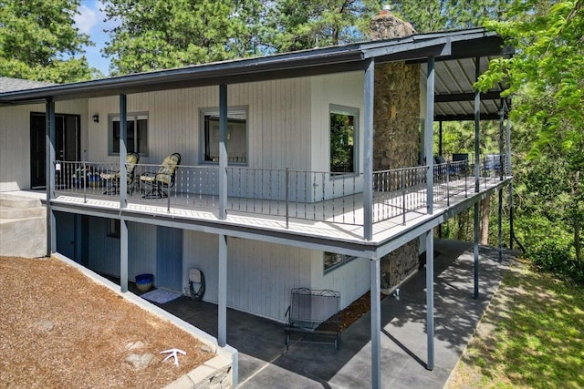 6913 S Ben Burr Rd, Spokane, WA 99223 - back of house featuring a chimney, a patio area, covered porch, and stone siding