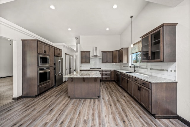 10697 N Crimson Dr, Hayden, ID 83835 - kitchen with appliances with stainless steel finishes, wall chimney exhaust hood, a sink, dark brown cabinetry, and a kitchen island