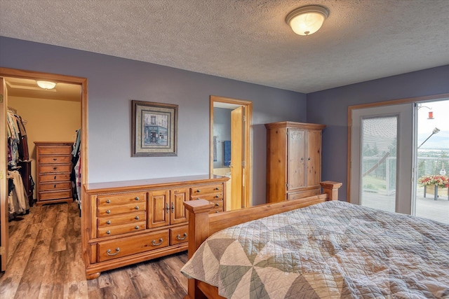 6930 N N Lynden Ln, Otis Orchards, WA 99027 - bedroom featuring a spacious closet, wood finished floors, a textured ceiling, access to exterior, and ensuite bathroom