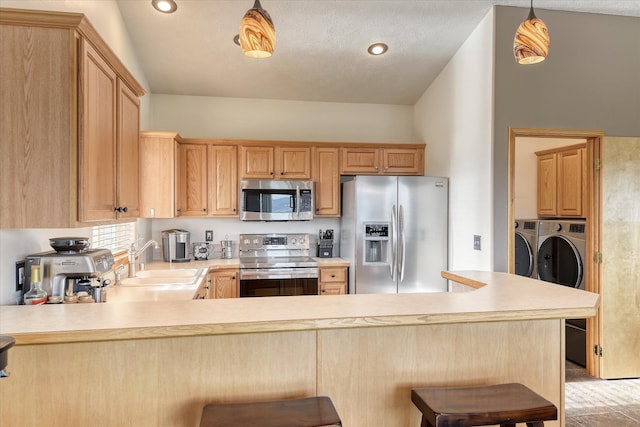 6930 N N Lynden Ln, Otis Orchards, WA 99027 - kitchen featuring stainless steel appliances, a sink, washer and clothes dryer, light countertops, and a peninsula
