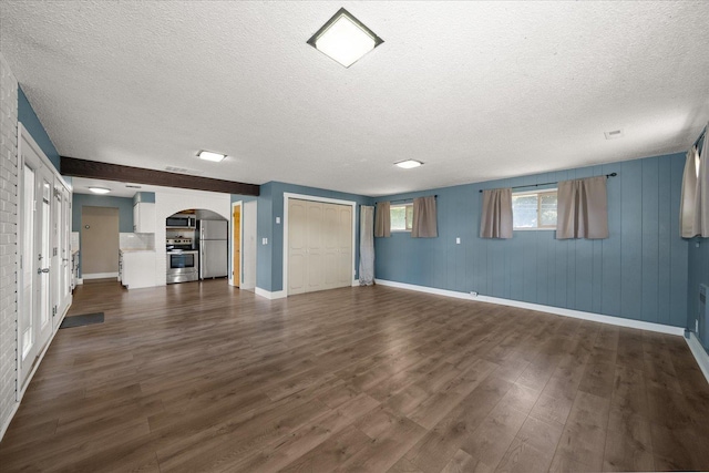 519 N Bannen Rd, Spokane Valley, WA 99216 - basement featuring arched walkways, freestanding refrigerator, a textured ceiling, dark wood-style flooring, and baseboards