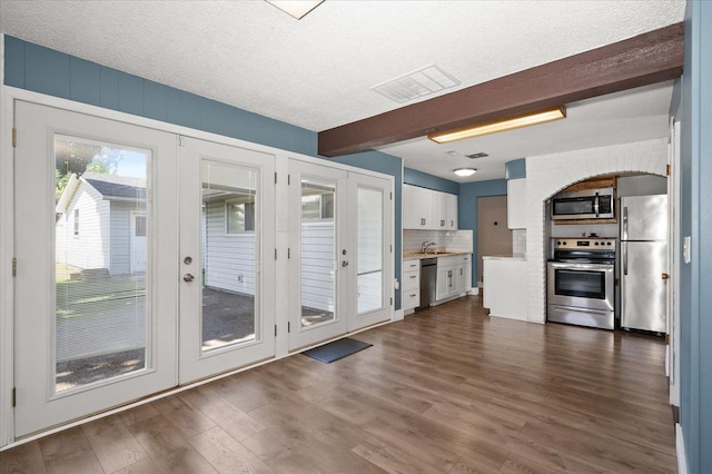 519 N Bannen Rd, Spokane Valley, WA 99216 - kitchen with appliances with stainless steel finishes, white cabinetry, beam ceiling, dark wood-style floors, and tasteful backsplash