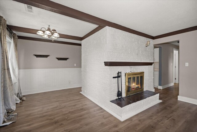 519 N Bannen Rd, Spokane Valley, WA 99216 - unfurnished living room featuring beamed ceiling, a fireplace, a wainscoted wall, a chandelier, and wood finished floors