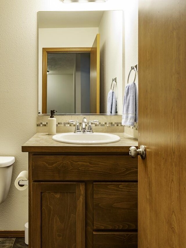 9705 E 4th Ave Unit 9707, Spokane Valley, WA 99206 - bathroom featuring toilet, vanity, backsplash, and baseboards