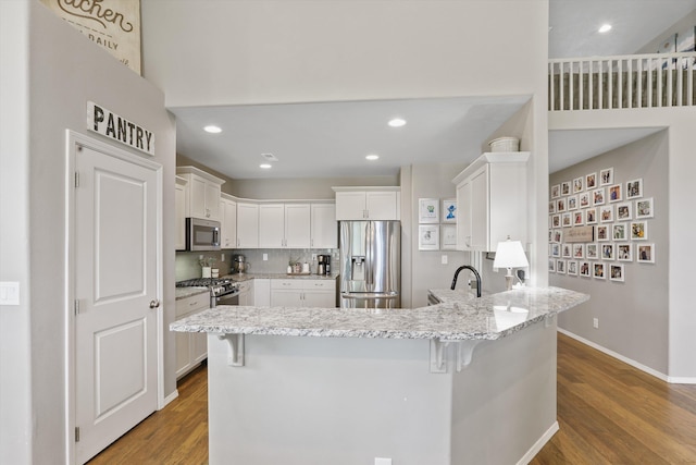 13616 W Pine Bluff Rd, Nine Mile Falls, WA 99026 - kitchen featuring appliances with stainless steel finishes, a peninsula, wood finished floors, white cabinetry, and recessed lighting
