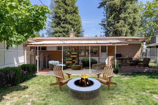 6721 N Howard St, Spokane, WA 99208 - rear view of house with an outdoor fire pit, brick siding, a lawn, a metal roof, and a chimney