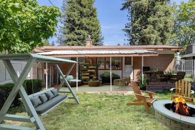 6721 N Howard St, Spokane, WA 99208 - back of house featuring an outdoor living space with a fire pit, brick siding, a lawn, a metal roof, and a patio area
